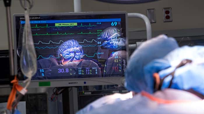 Surgical team reflected on vitals monitor in operating room