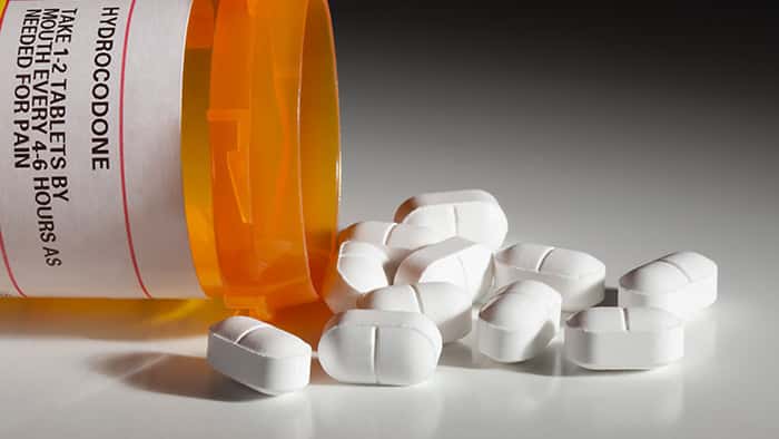 Whites pills spilling out of prescription bottle