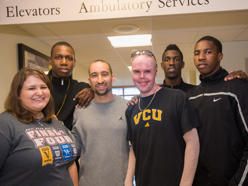 Tony and his wife, Sharon, posing with head coach Shaka Smart and members of the VCU men's basketball team at the Evans-Hayes Burn Center