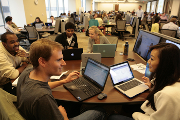 Students talking at a table with laptops
