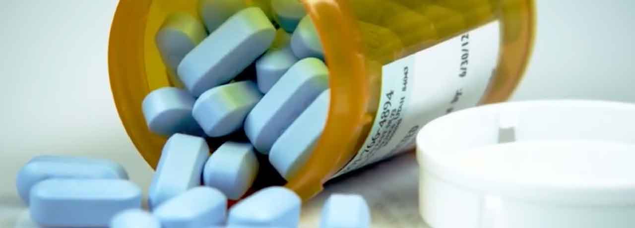 Blue pills spilling out of medicine bottle.