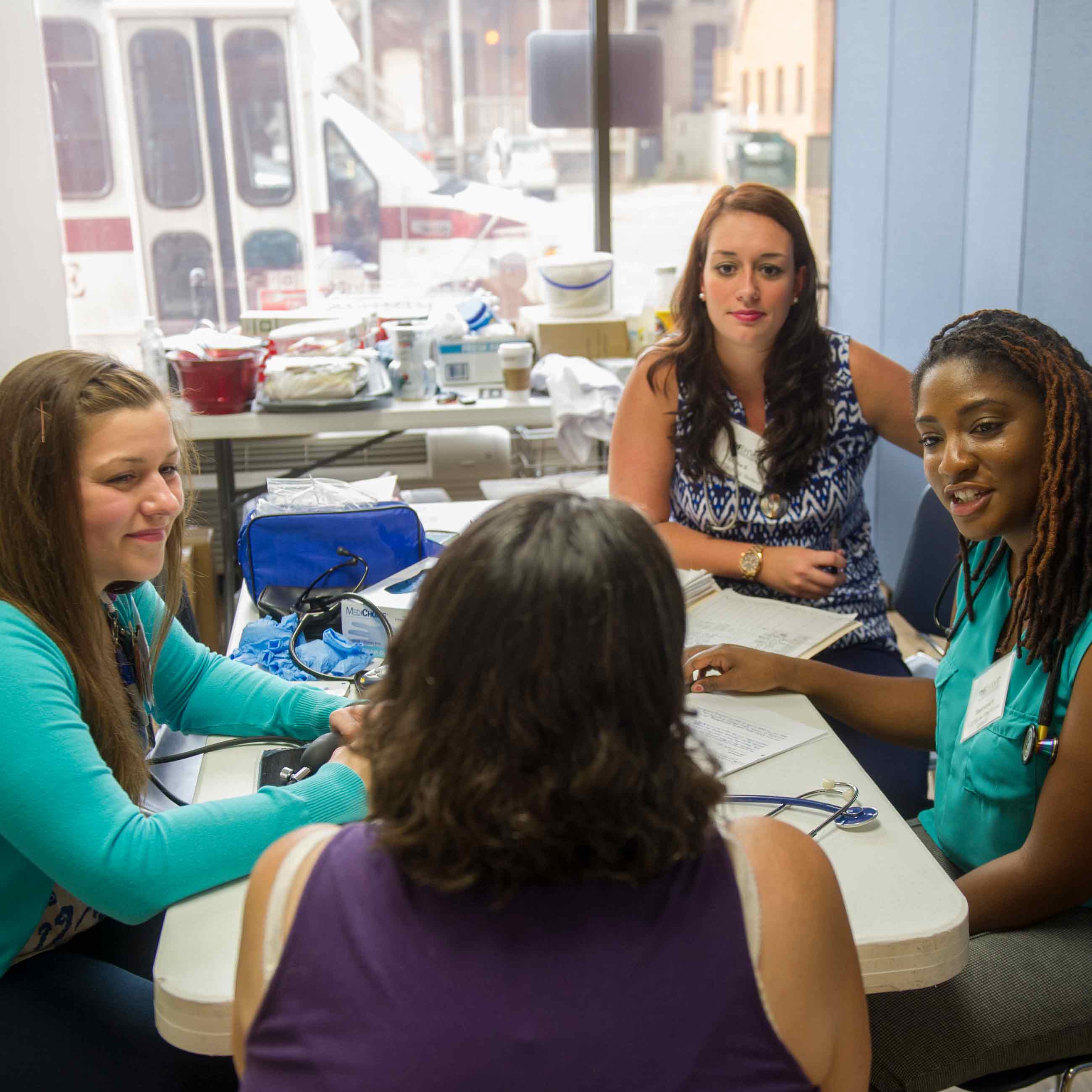 Four students sitting around small table, discussing patient outcomes