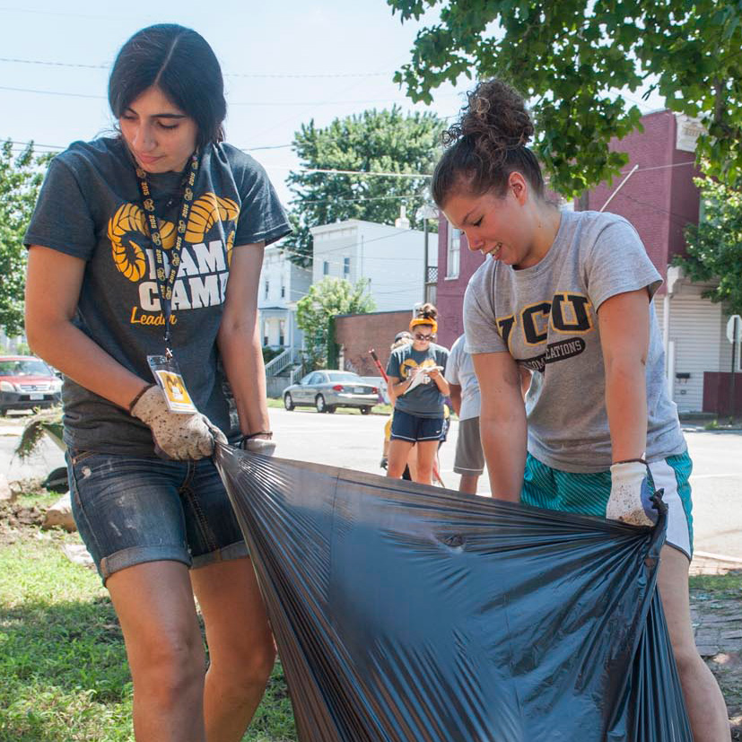 Two students holding trash bag as part of service project in area neighborhood