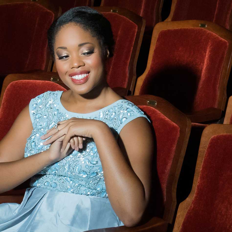 Student dressed in light blue sequined gown seated in theater