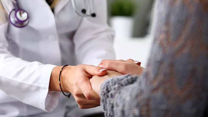 Physician holding hands with patient