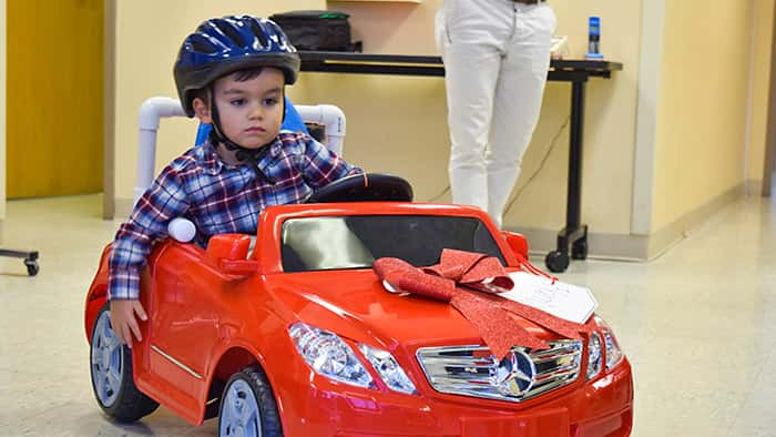 Child in mobility enhanced toy car