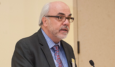 Male physician-scientist-in-residence John E. Nestler, M.D. in a suit and tie giving a speech.