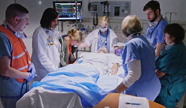 Hospital staff standing silently and still around a patient who has passed away.