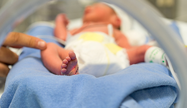 A small premature baby in an incubator.