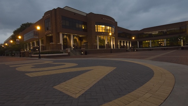 VCU Student Commons captured during dusk. The foreground features a brick plaza with a large VCU inlaid design.
