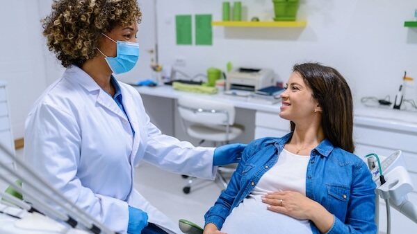 A pregnant patient smiling while conversing with a doctor.